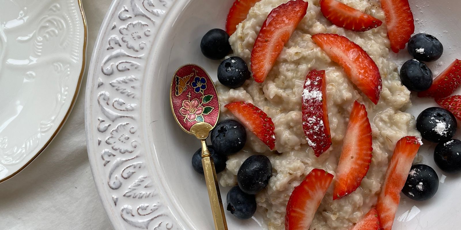 A bowl of oatmeal topped with fresh strawberries and blueberries
